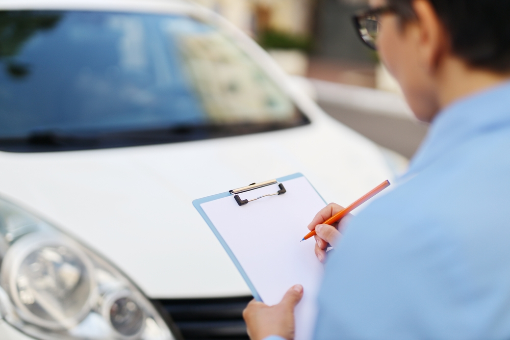Buying a Used Car From Someone Whose Name Isn’t on the Title? Check These Things First Buyer reviewing title document before buying a used car